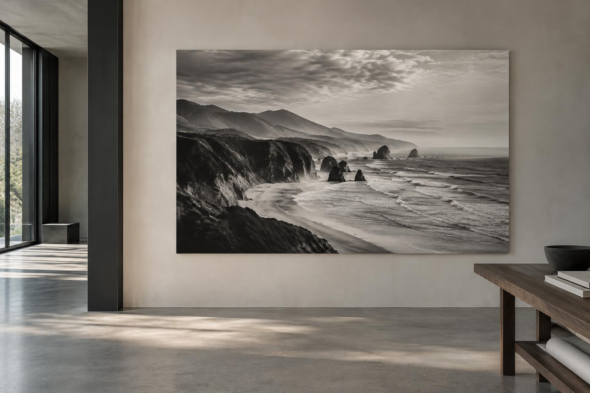 A large monochrome coastal fine-art print displayed in a refined contemporary studio